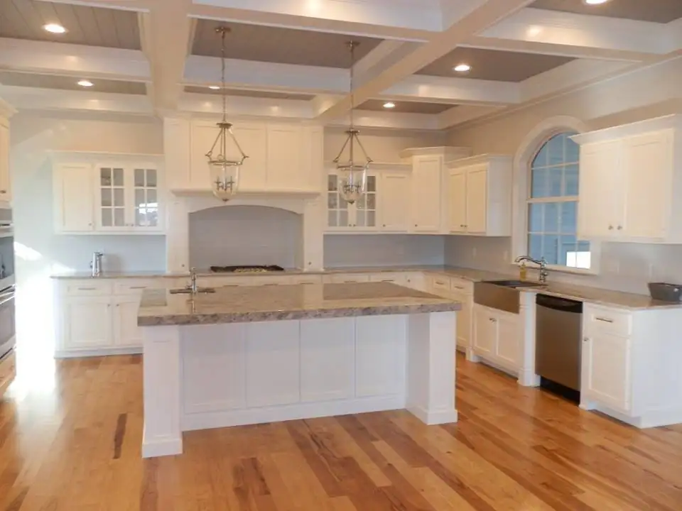 White kitchen with a coffered ceiling, lantern pendants, a large granite island, apron-front sink and hickory floors, kitchen cabinets Russellville